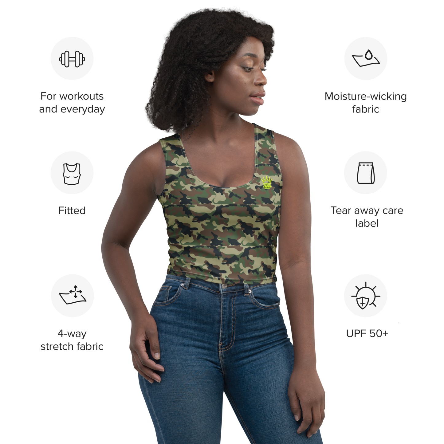 A woman with dark curly hair wears the CROWN PICKLEBALL - Women's Corona Crop-top (Camo) by Crown Pickleball and blue jeans, highlighted for workouts/everyday, fitted design, 4-way stretch, moisture-wicking microfiber, tear-away label, and UPF 50+.