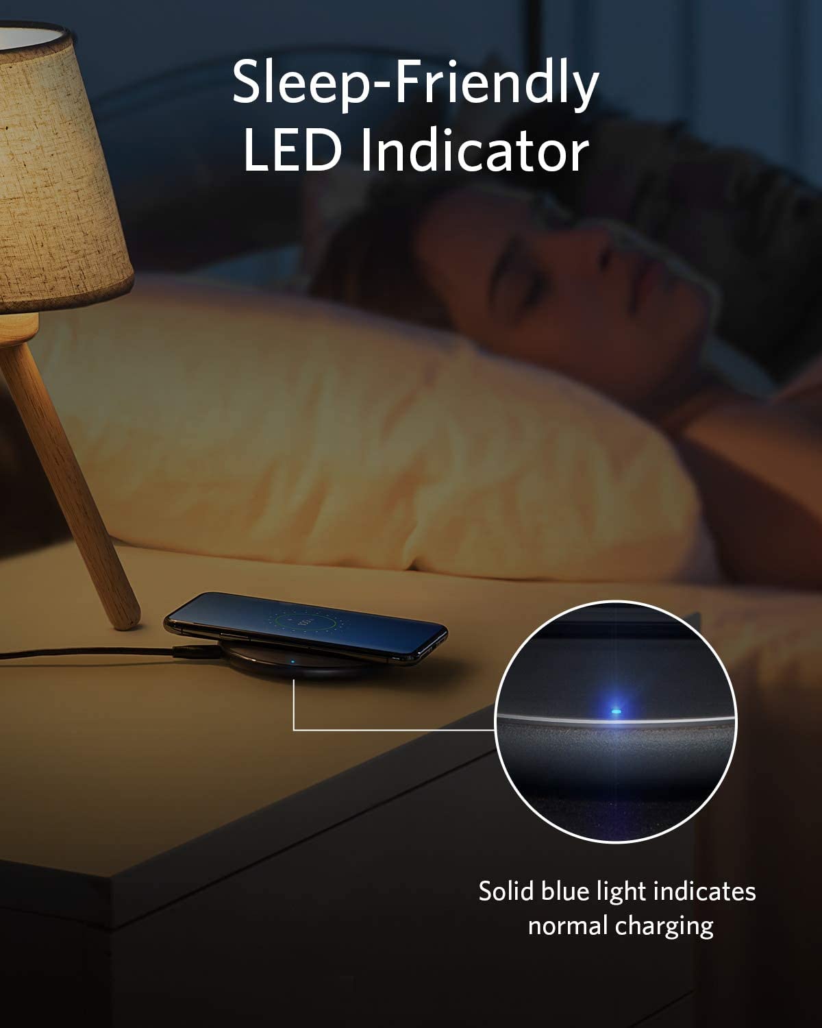 A woman sleeps beside a nightstand with an Anker 313 Wireless Charger (Pad) by Anker, its soft blue LED glowing. Text reads: “Sleep-Friendly LED Indicator—solid blue means normal charging.”.