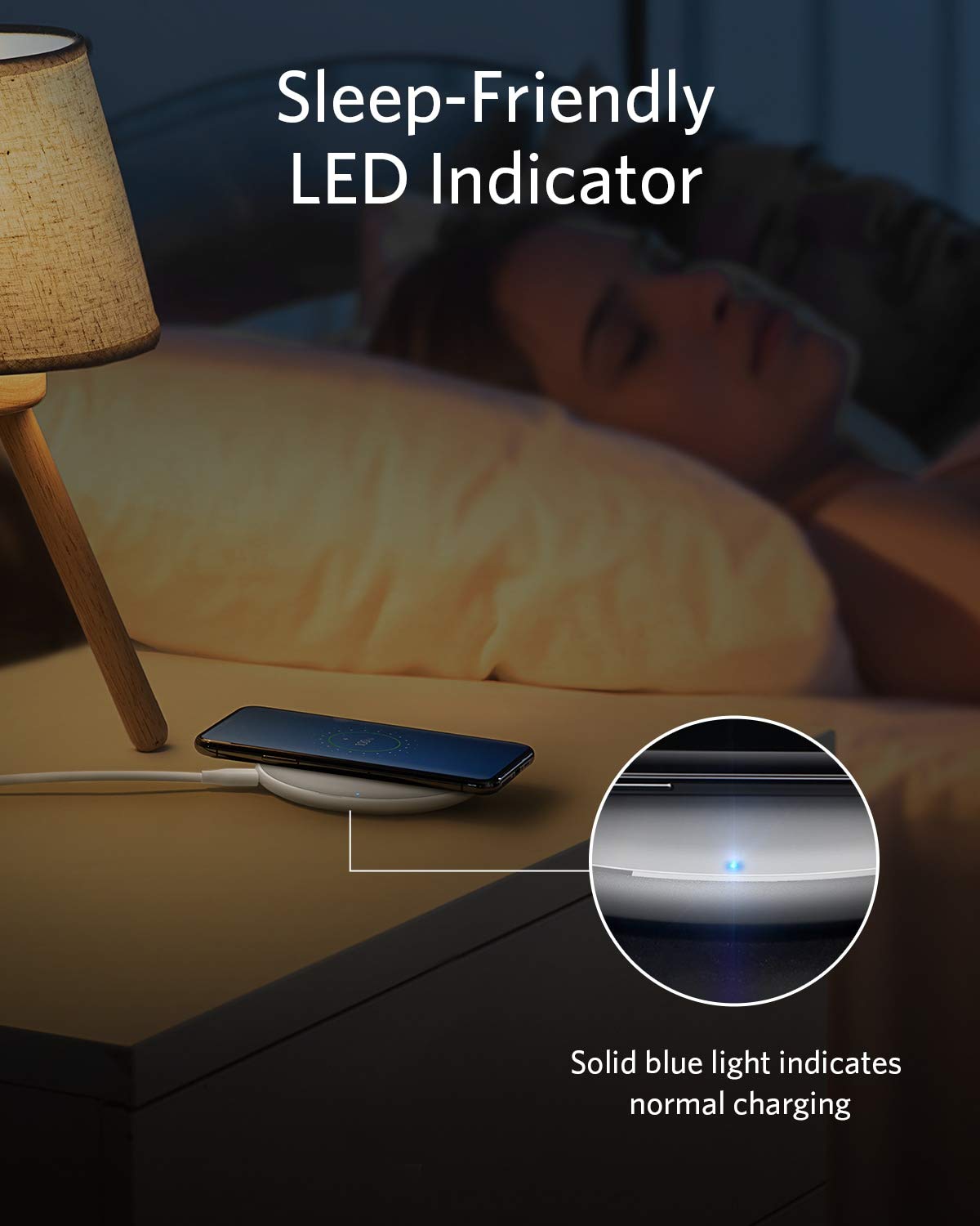 A woman sleeps in a dim room as her phone charges on the Anker 313 Wireless Charger (Pad) by Anker, its gentle blue LED softly glowing. Text reads: “Sleep-Friendly LED Indicator” and “Solid blue light means normal charging.”.
