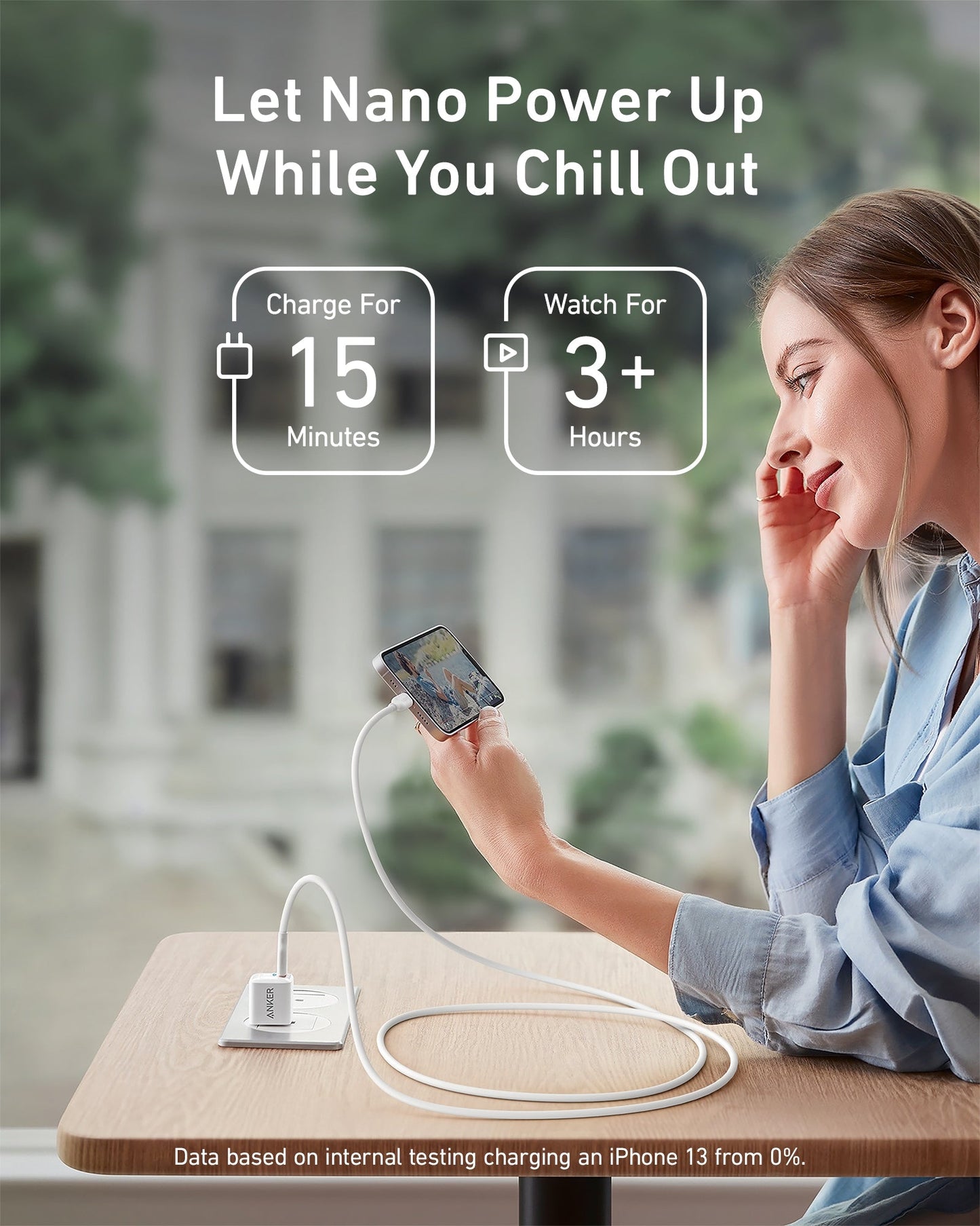 A woman relaxes at a table, smiling at her phone as it charges with the Anker 511 Charger (Nano) and USB-C to Lightning Cable. Text: Let Nano Power Up While You Chill Out. 15 Minutes of Charging = 3+ Hours of Watching.