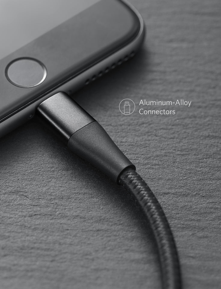 A close-up of a smartphone with the Anker 551 USB-A to Lightning Cable inserted. The screen is off, displaying a circular home button. Beside the cable, text highlights its “Aluminum-Alloy Connectors” and MFi certified design.