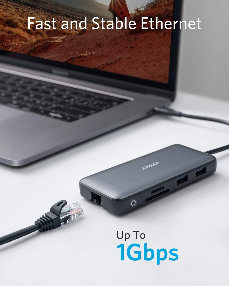 A laptop connects to the black Anker 553 USB-C Hub (8-in-1) with Ethernet, SD card, and USB ports. An Ethernet cable is attached. Text: “Fast and Stable Ethernet,” “Up To 1Gbps,” and “Power Delivery.” Brand: Anker.