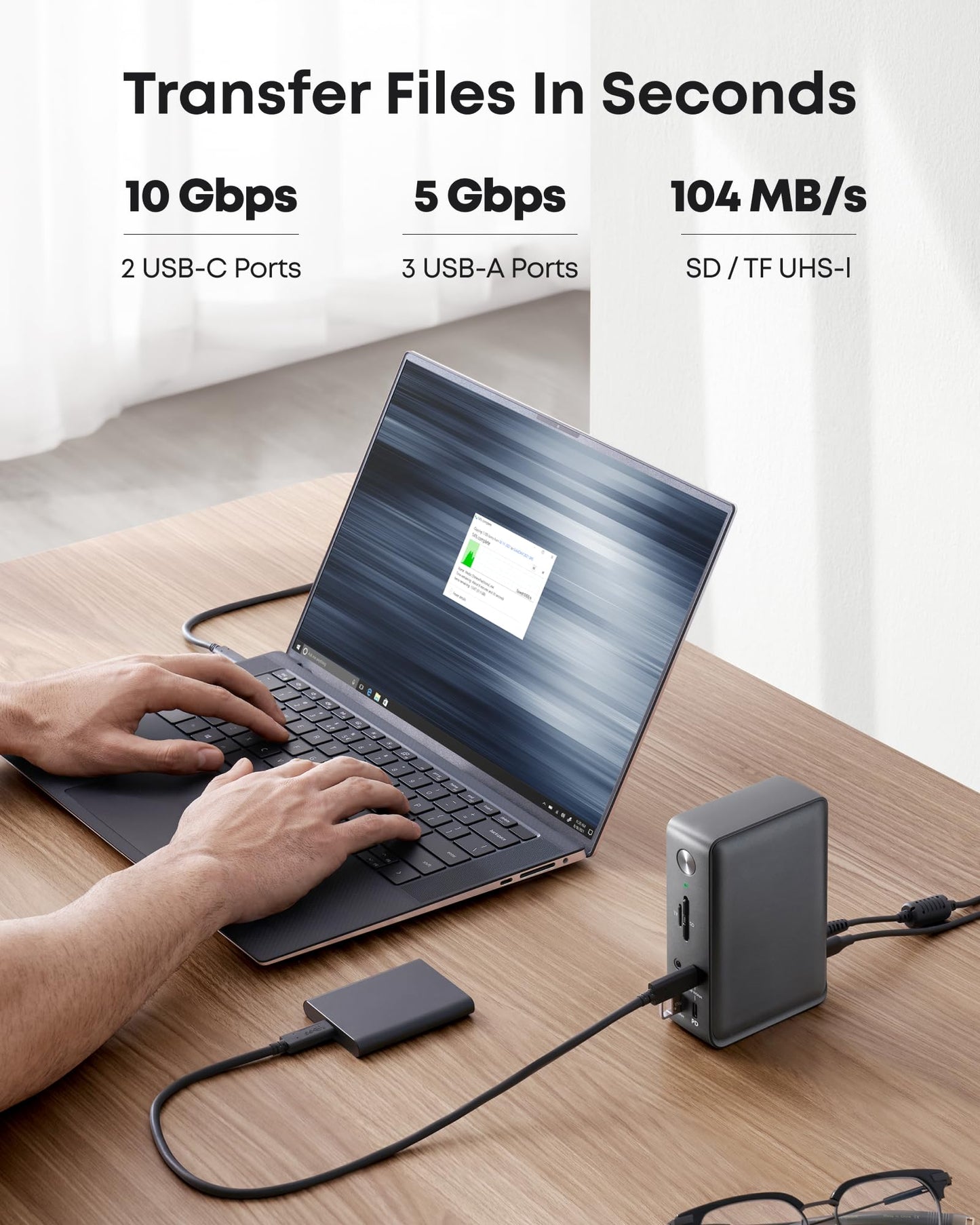 Using the Anker 575 USB-C Docking Station (13-in-1), users can transfer files in seconds at up to 10 Gbps, charge their laptop, and connect up to three displays—all from one device on a wooden desk.