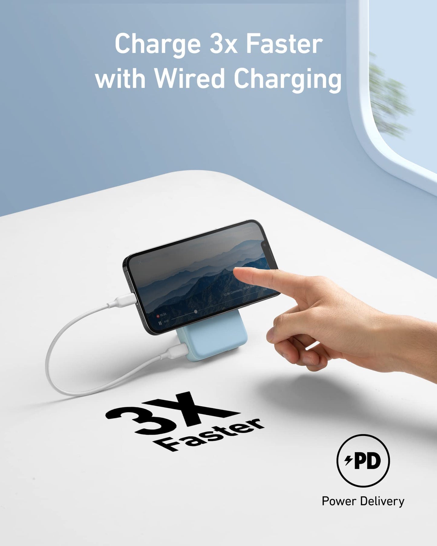 A hand touches a smartphone on a blue Anker 633 Magnetic Battery, connected by a charging cable. Text above reads, “Charge 3x Faster with Wired Charging.” On the table are icons for 10,000mAh, PD Power Delivery, and 3x Faster. The phone shows mountains.