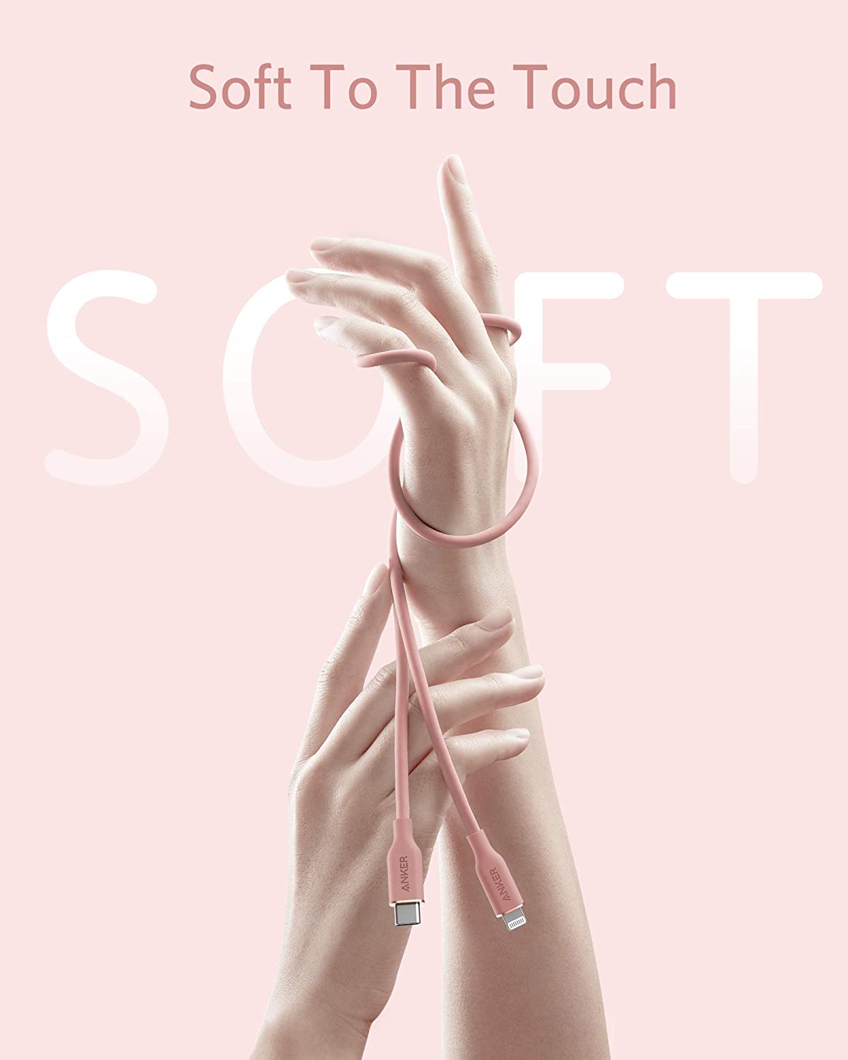 A pink Anker 641 USB-C to Lightning Cable (Flow, 3 ft Silicone) softly loops around two hands on a pastel background, with “Soft To The Touch” and a faded “SOFT” emphasizing Anker’s gentle, flexible silicone cable design.