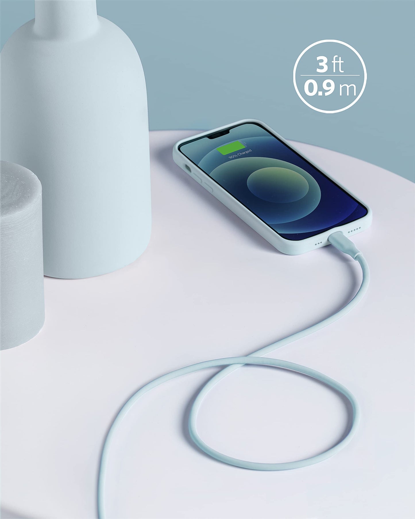 An Anker 641 USB-C to Lightning Cable (Flow, Silicone) in light blue charges a smartphone on a table beside a matte bottle and cylinder. A graphic highlights its 3 ft (0.9 m) length as the phone displays a charging icon.