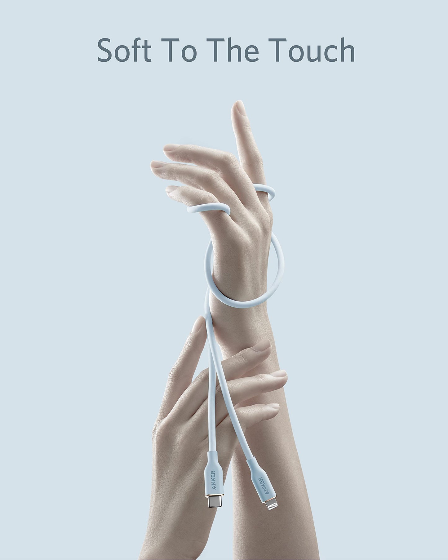 A pastel blue Anker 641 USB-C to Lightning Cable (Flow, Silicone) gently wraps around a raised hand and wrist while another hand touches it. Against a light blue background, bold text reads "Soft To The Touch" in a soft, minimalistic style.