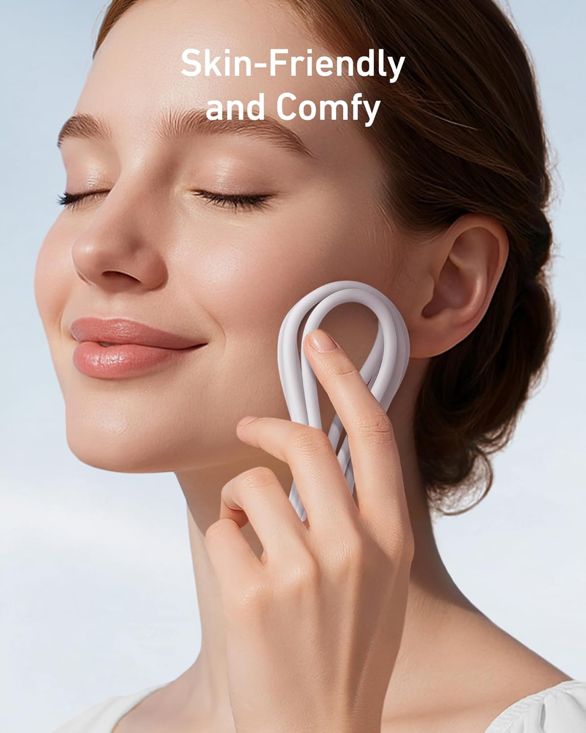 A smiling woman gently massages her cheek with a white, loop-shaped item. Above her, white text reads "Skin-Friendly and Comfy." She looks relaxed—just like when using the Anker 643 USB-C to USB-C Cable (Flow, Silicone) by Anker.