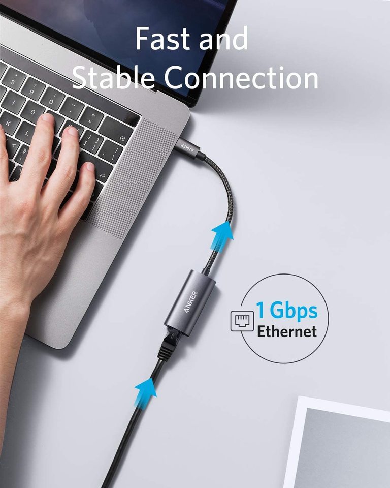 A left hand uses a silver laptop connected by the Anker <b>PowerExpand</b> USB-C to Gigabit Ethernet Adapter to a black Ethernet cable. “Fast and Stable Connection” and “1 Gbps Ethernet” appear, with blue arrows showing instant internet on a light gray surface.