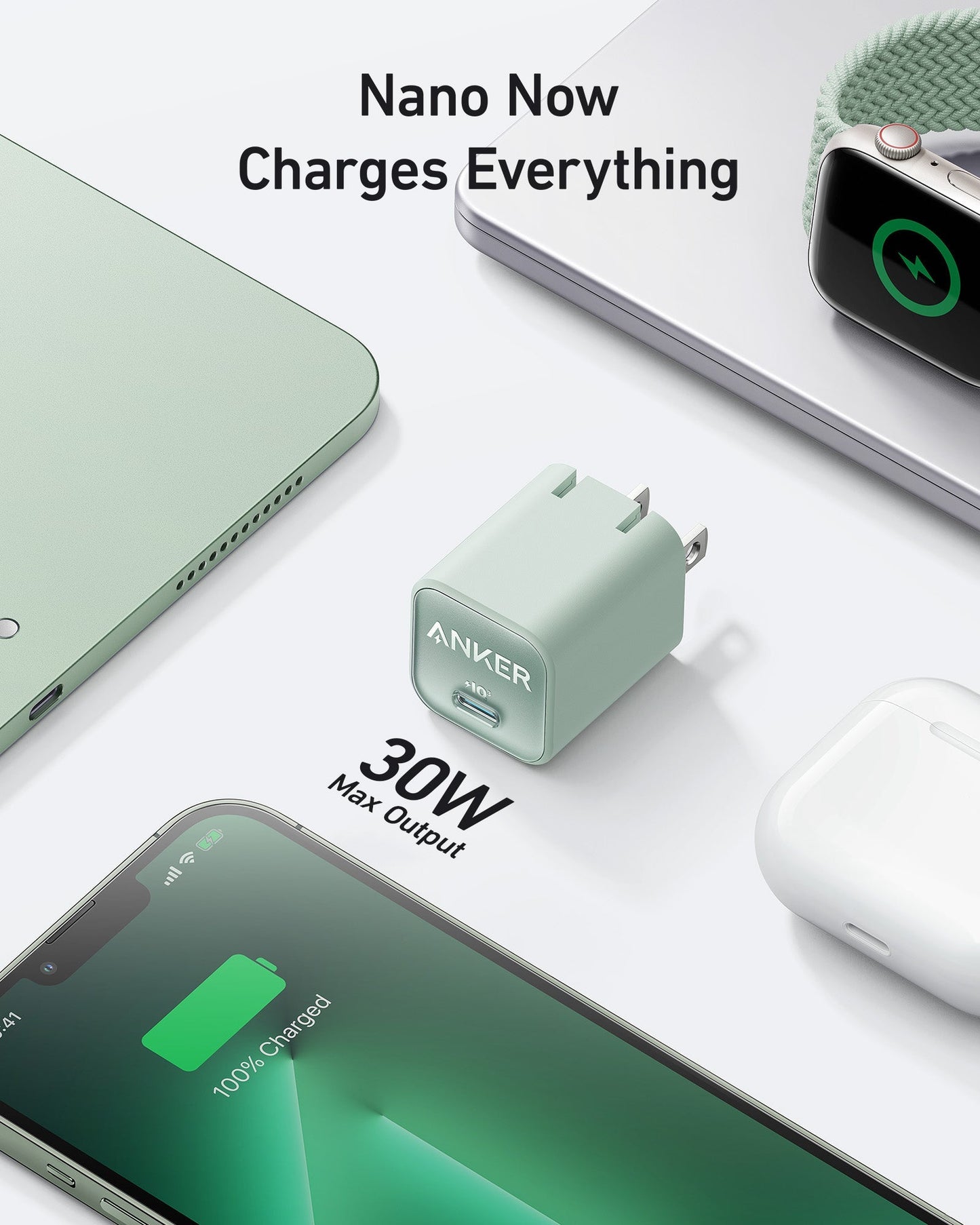 A mint green Anker Nano Charger (30W) rests on a white surface near a green laptop, Apple Watch, AirPods, and a fully charged iPhone. Above it, the text reads: “Nano Now Charges Everything.” Brand: Anker.