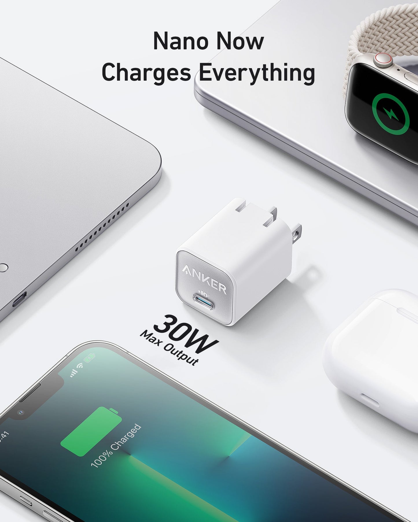 A white Anker Nano Charger (30W) by Anker is shown quickly charging a laptop, smartwatch, AirPods, and smartphone—all at 100%. The text above says, “Nano Now Charges Everything.” Devices are neatly arranged on a white surface.