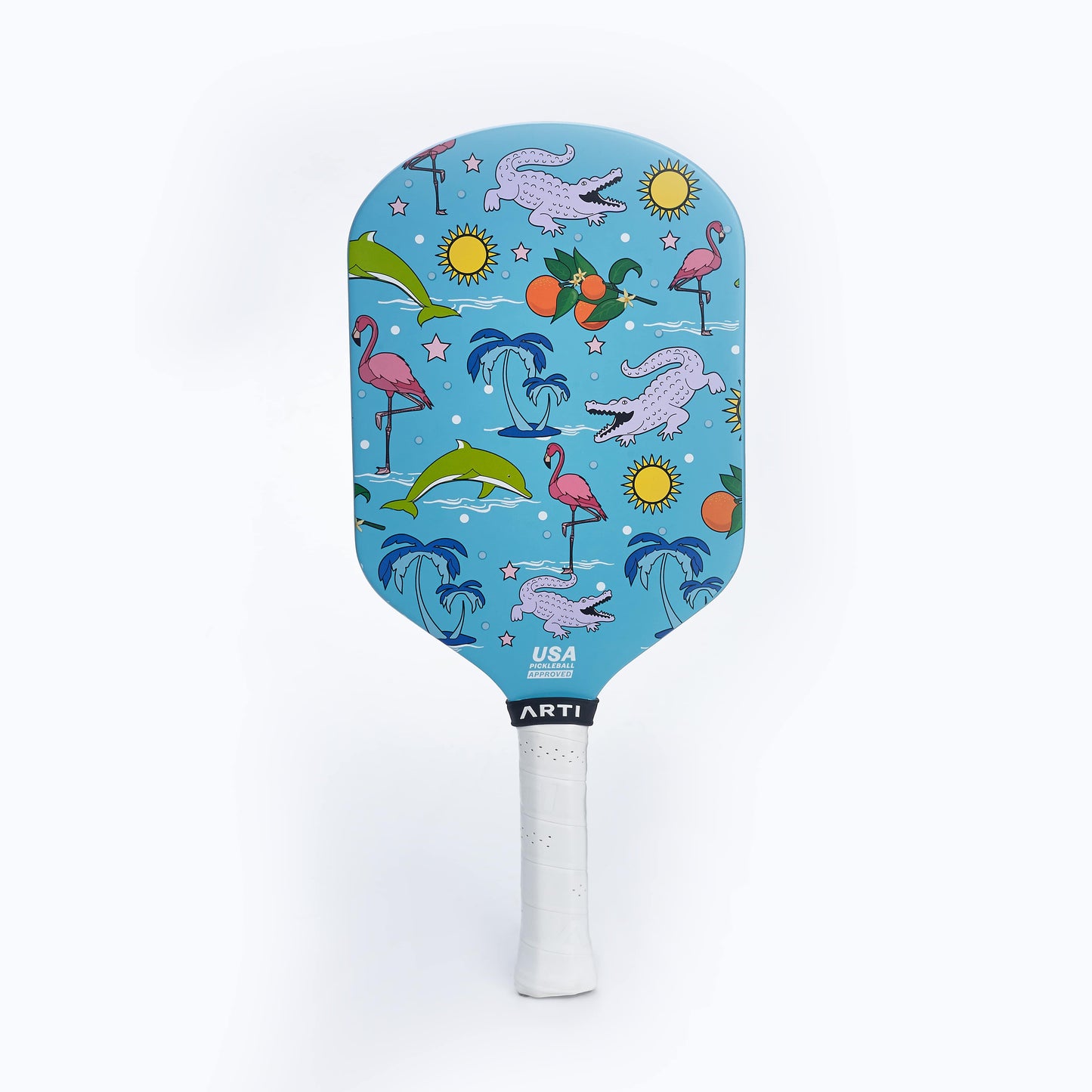 The ARTI Carbon Fiber "FLORIDA" Paddle by ARTI features a light blue background with flamingos, alligators, dolphins, oranges, suns, and palm trees. It has a white grip and displays the USAPA approved paddle logo near the grip.