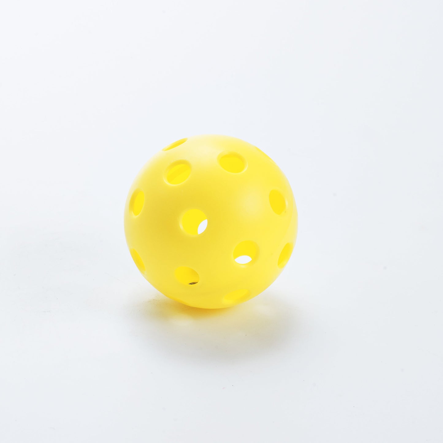 The ARTI Indoor Pickleball by ARTI is a bright yellow ball with large, smooth-edged holes designed for indoor play. Its durable construction and evenly spaced circular holes make it perfect for the court, shown here on a plain white surface.