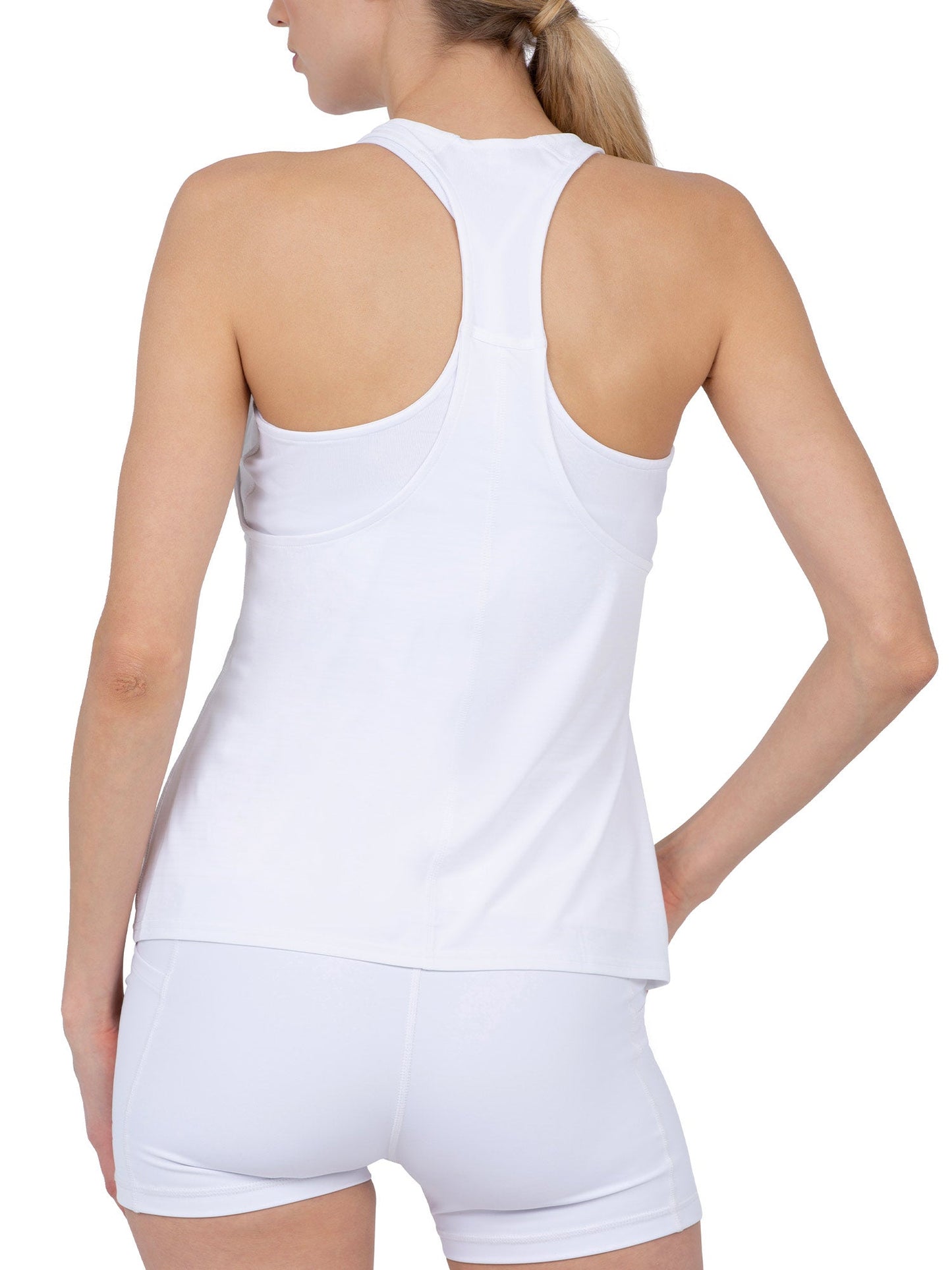 A woman with a ponytail is seen from the back wearing the inPhorm NYC Aubrey Double Layer Athleisure Tank in white (UPF 50+) and fitted shorts. Her left hand rests on her hip against a plain white background.