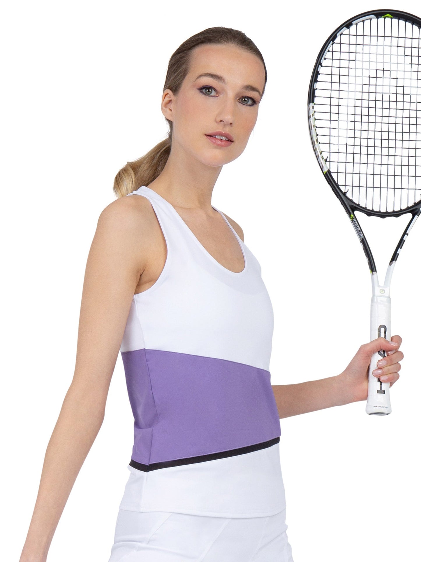 A woman with light skin and straight blonde hair pulled back, wearing the inPhorm NYC Baseline Tank - White/Lavender Combo and a white skirt, holds a tennis racket against a plain white background.