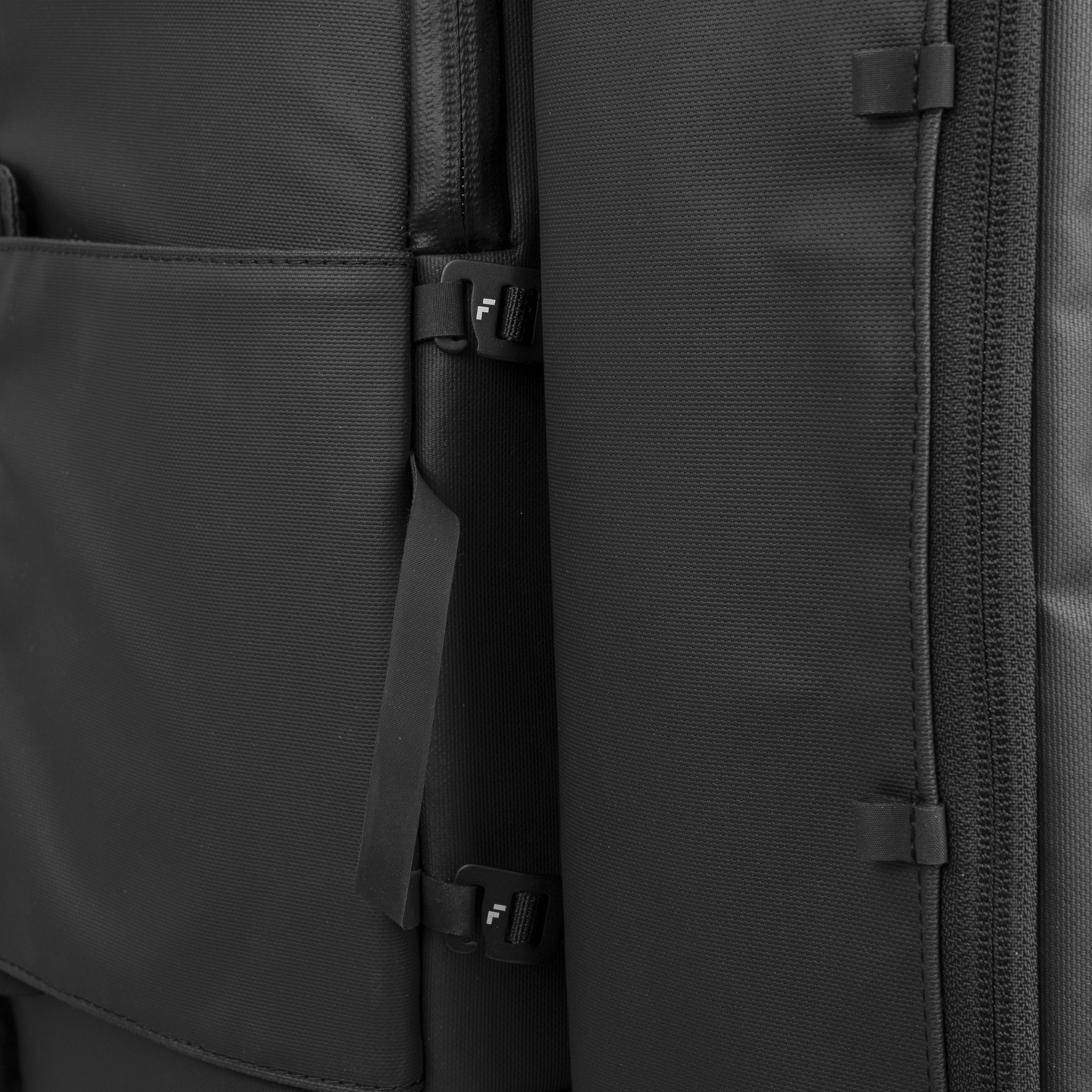 Close-up of a black fabric suitcase featuring two plastic buckle clips and textured panels. Durable material and secure fastening—ideal for use with the FORWRD Court Caddy Shoe Cube while traveling.