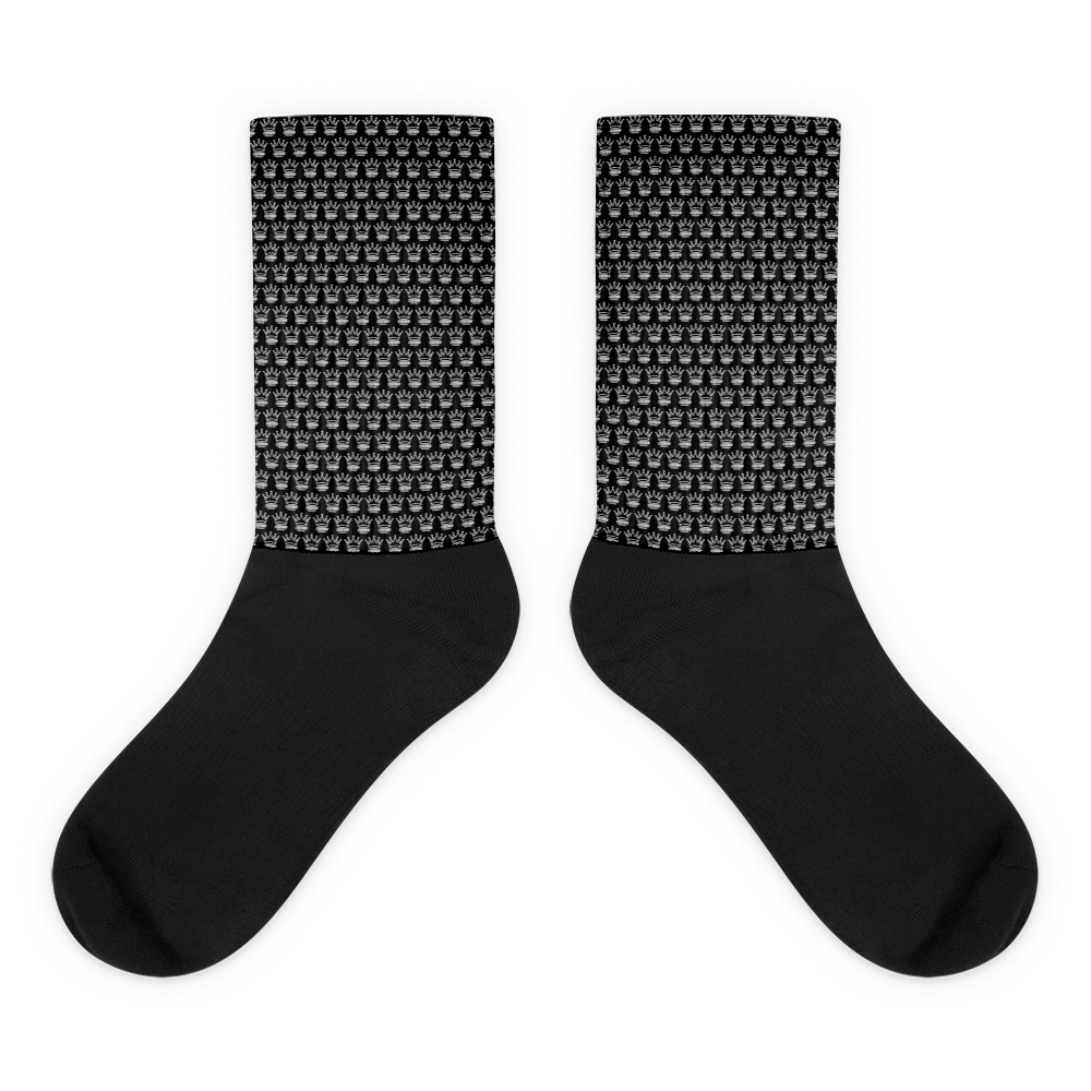 The CROWN PICKLEBALL - Checkered Crown (Black) socks by Crown Pickleball feature a repeated white pixel crown pattern on the upper black crew, with solid black foot and toe sections, displayed flat side by side on a white background.