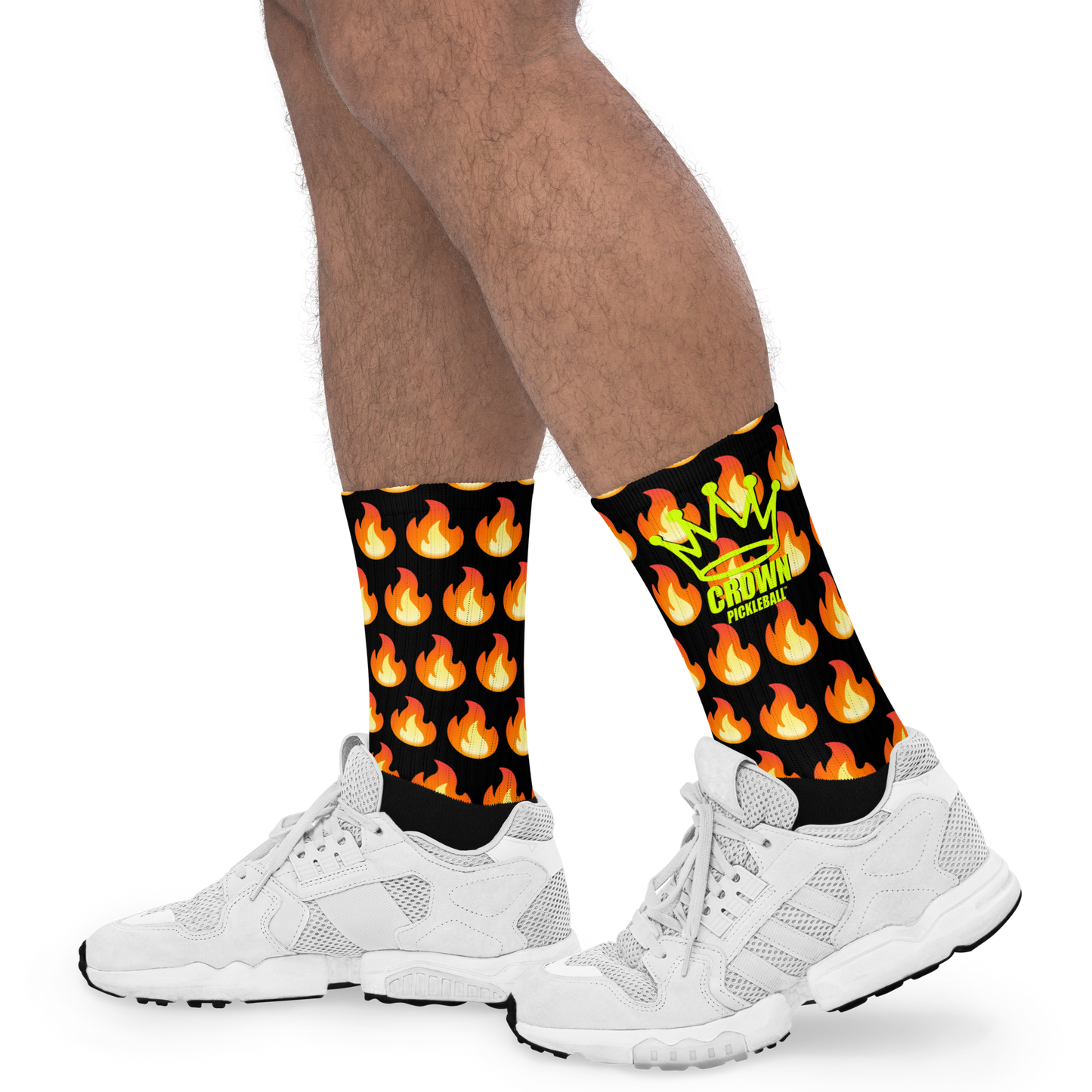 A person sports white sneakers and Crown Pickleball's Performance Athletic Crew Socks, black with orange flames, a green crown, and "CROWN PROLIFIC" in yellow—all set against a plain white background.