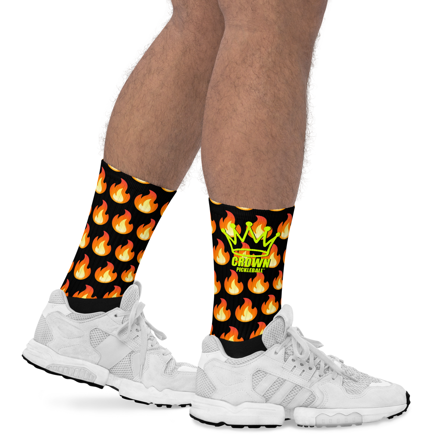 A person sports Crown Pickleball's Performance Athletic Crew Socks—white, cushioned, and adorned with a yellow-green crown, CROWN PICKLEBALL text, and orange flame icons—showcased on a plain white background.