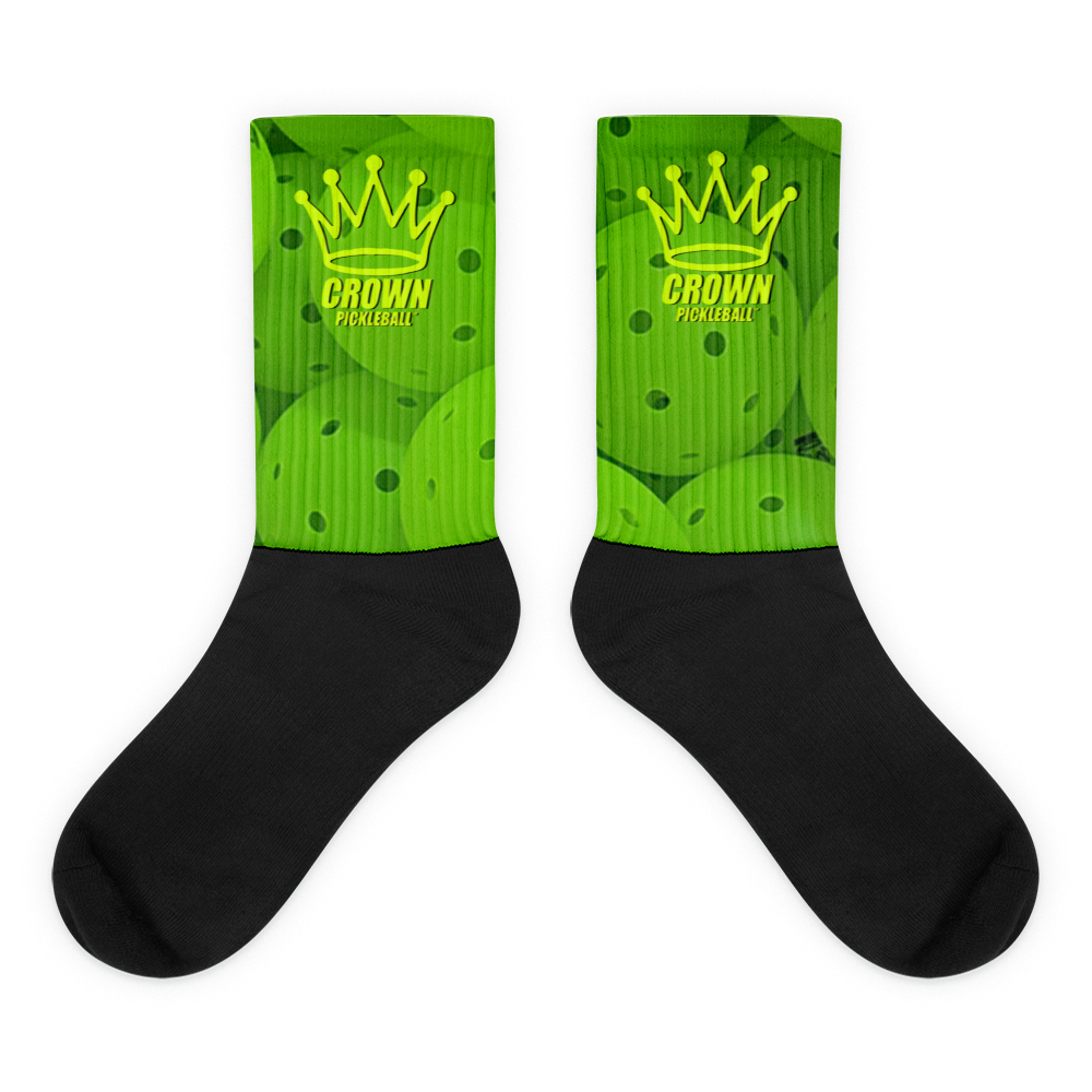 The CROWN PICKLEBALL - Performance Athletic Crew Socks by Crown Pickleball feature black feet, vivid green uppers with overlapping pickleballs, a yellow crown graphic, and "CROWN PICKLEBALL" text—perfect for every pickleball enthusiast.