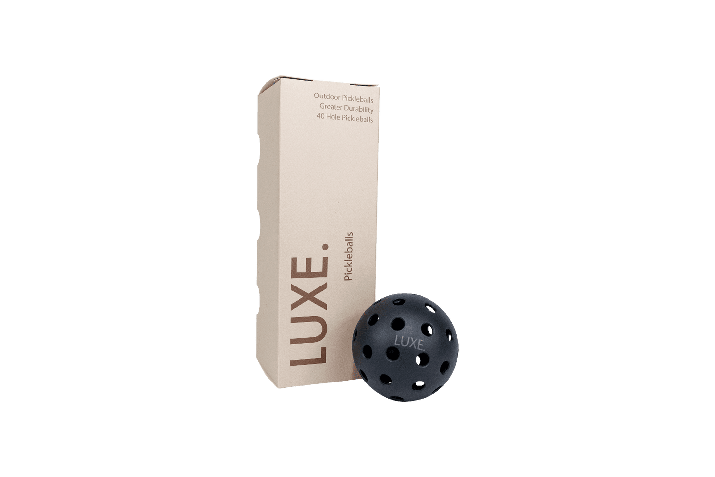 A beige rectangular LUXE Pickleball box labeled "Black Pickleballs - Pack of 3" stands upright beside a black ball printed with LUXE. The box notes 40-hole outdoor balls for increased durability, all set against a plain white background.