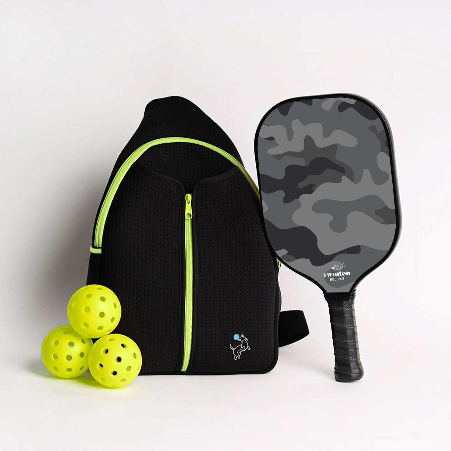 The Swinton Pickleball Starter Bundle - Black Sling Bag Combo features a black backpack with neon green accents, three yellow pickleballs, and a stylish paddle—an ideal pickleball gift that stands out against the plain white background.