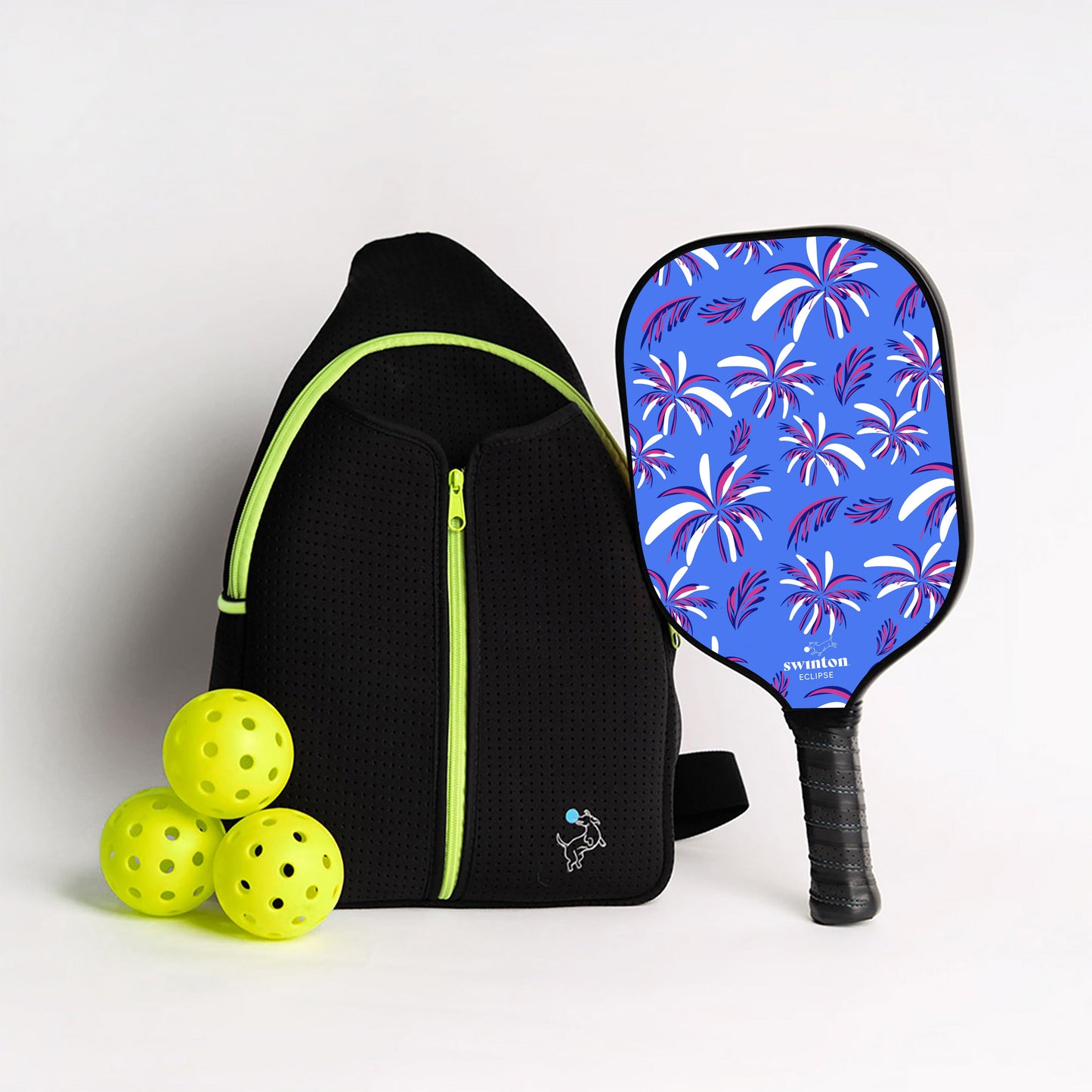 The Swinton Pickleball Starter Bundle - Black Sling Bag Combo includes a sleek black zippered sports backpack, three yellow pickleballs, and a blue-purple palm leaf paddle—an eye-catching pickleball gift set.