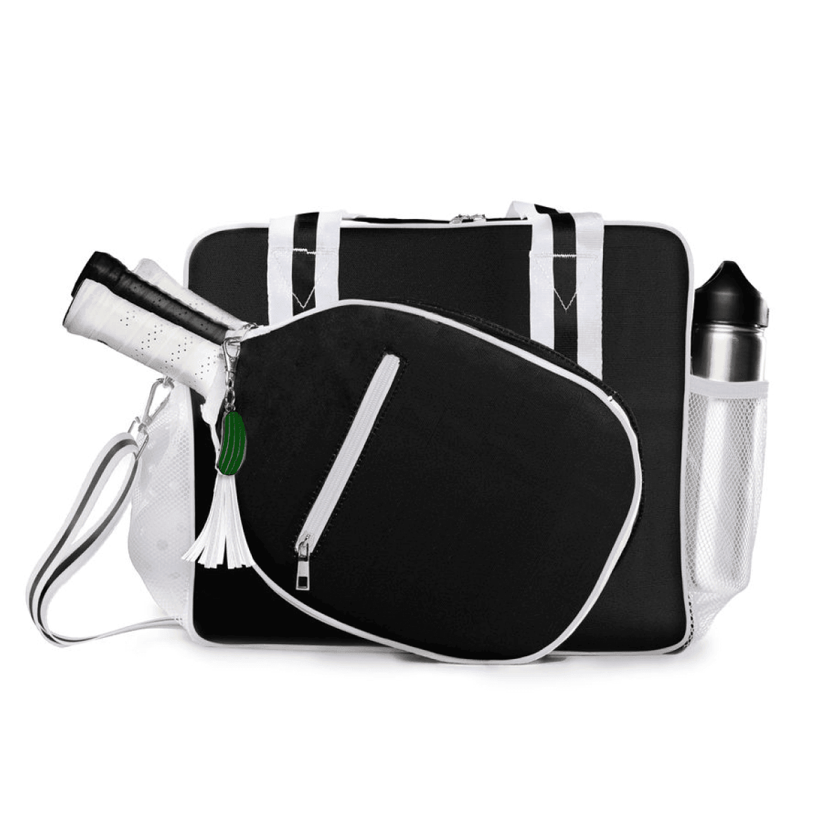 The Lola Pickleball Tote Bag by Fresh Pickle is shown in black and white with a racket in the front pocket. A white tassel keychain and green charm hang from the zipper. It features a shoulder strap and mesh water bottle pocket, set on a white background.