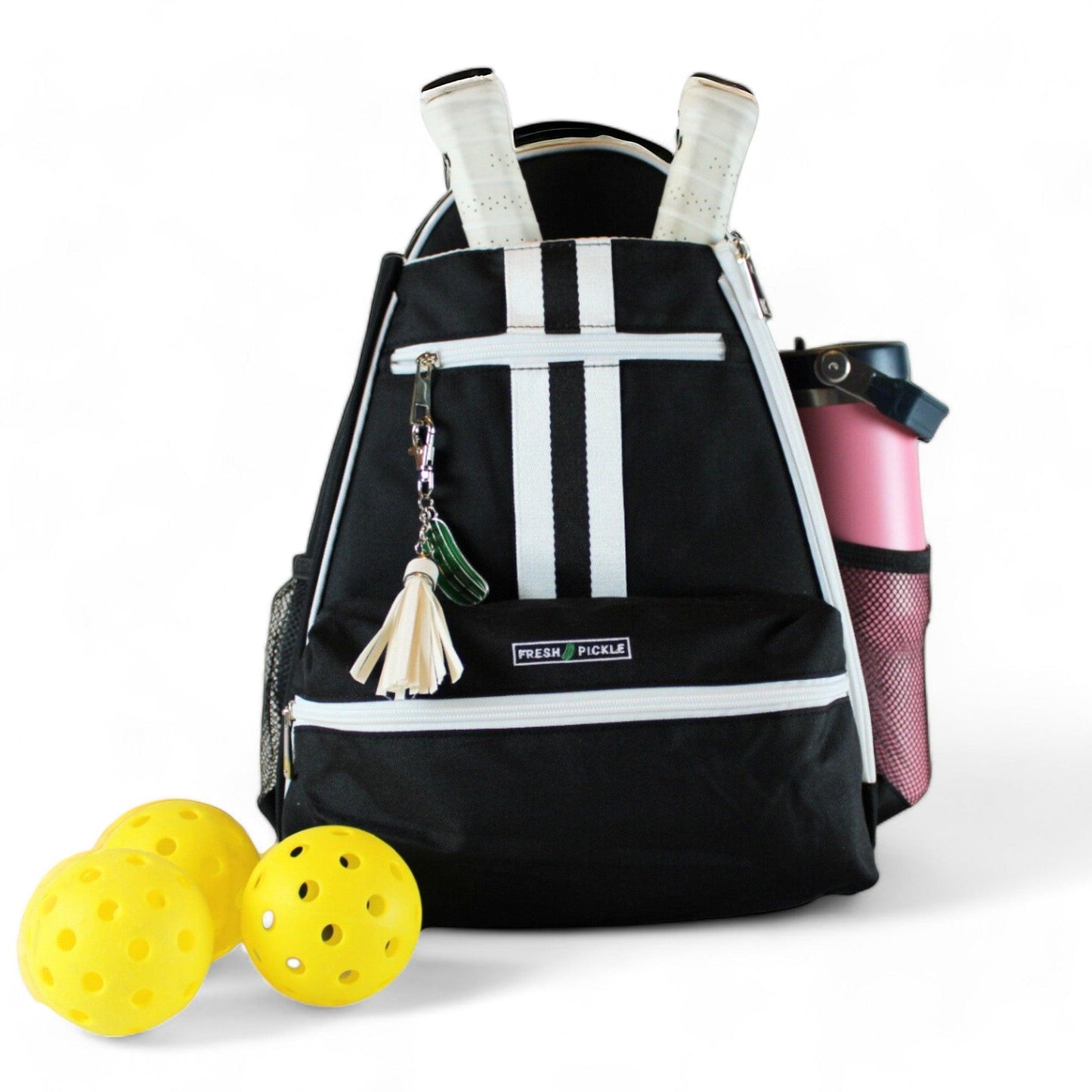 The Teddi Pickleball Backpack by Fresh Pickle, shown on a white background, holds two white paddles, a pink water bottle in the side mesh pocket, a tassel keychain on the zipper, and three yellow pickleballs placed in front.