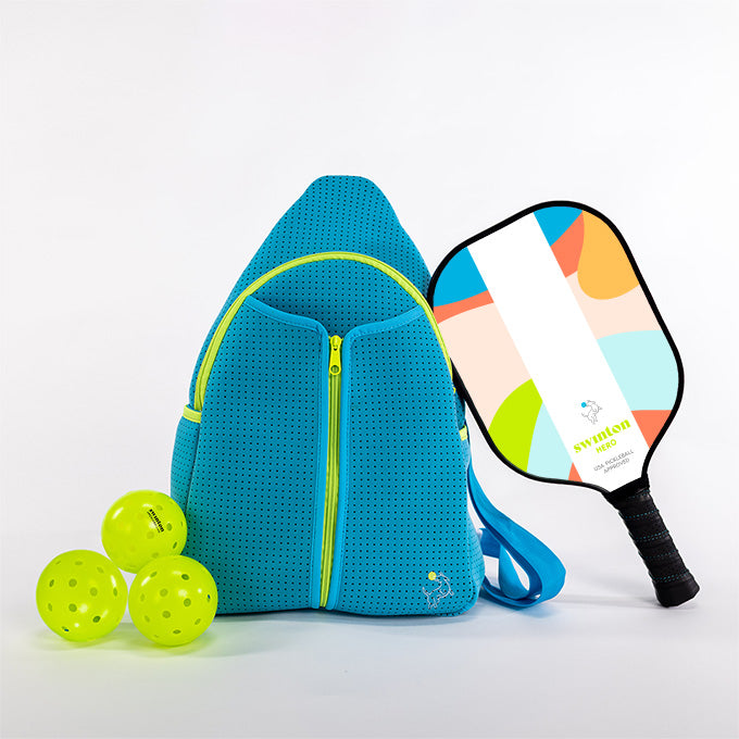 The Swinton Pickleball Pickleball Starter Bundle - Blue features a blue zippered backpack, three yellow pickleballs, and a colorful paddle with a black grip, all neatly arranged on a white surface against a plain background.