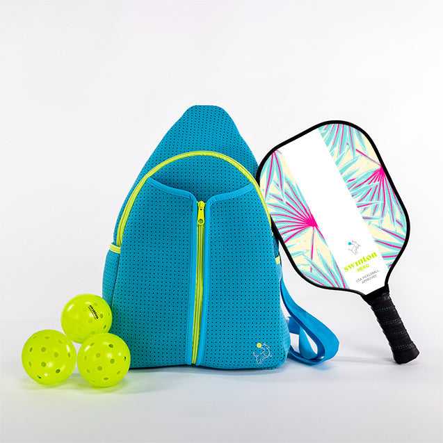 The Swinton Pickleball Starter Bundle - Blue features a bright blue backpack with yellow zippers, a palm leaf design paddle, and three neon yellow pickleballs—everything you need to start playing, displayed against a white background.