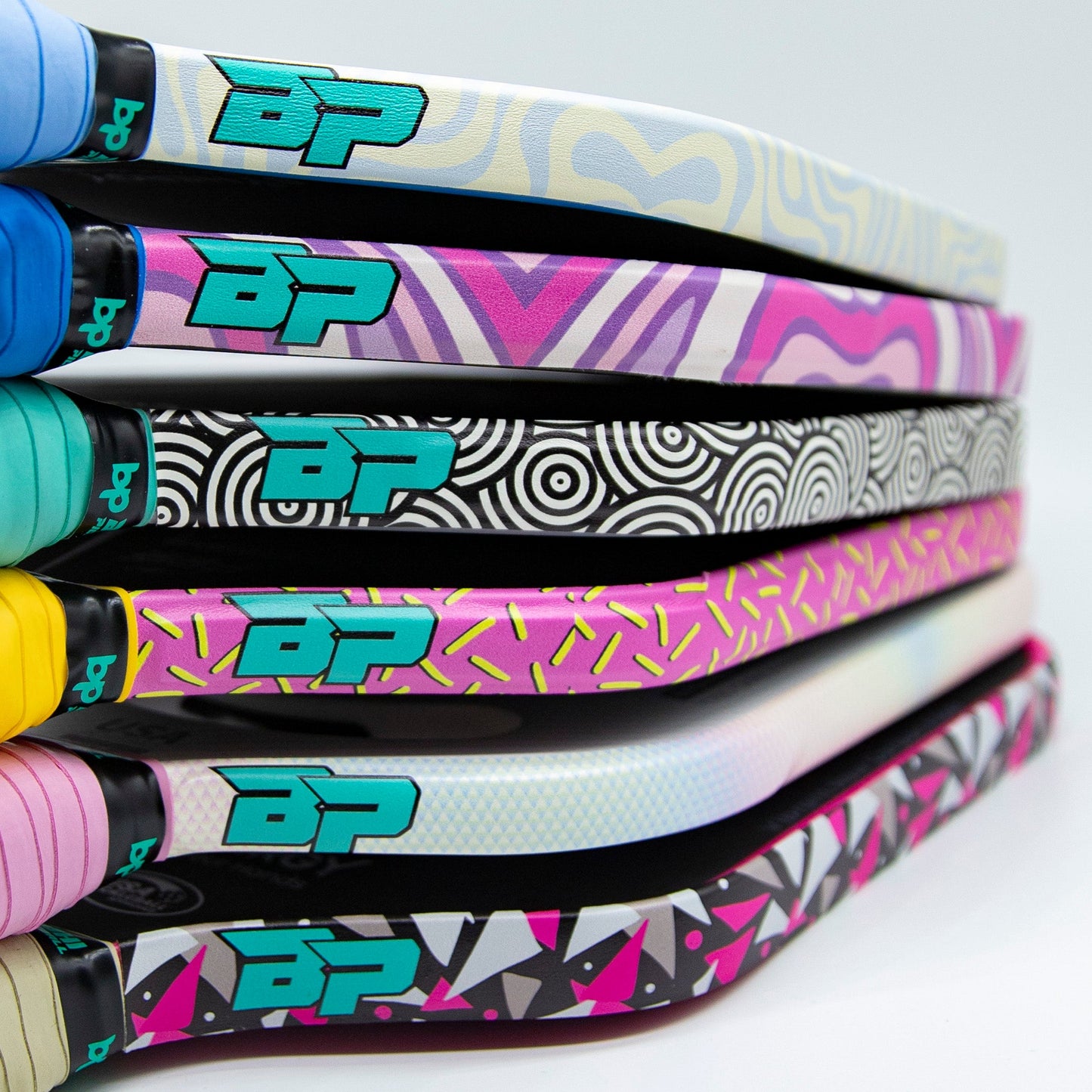 Five Bodhi Performance Premium Edge Tapes, each with unique designs and pastel grips, are stacked. Bold BP logos and vibrant colors add style, while premium edge tape ensures professional protection for every pickleball paddle handle.