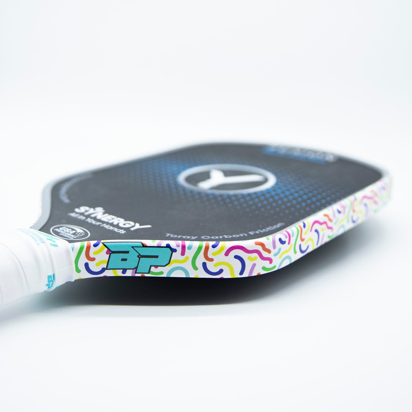 Close-up of a pickleball paddle with Bodhi Performance - Premium Edge Tape for Professional Edge Guard Protection. The colorful, wavy tape adds style and reliable protection. Handle is wrapped in white grip tape; Bodhi Performance branding appears on the face.