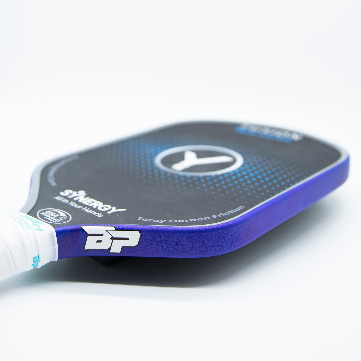Close-up of a black and blue Bodhi Performance pickleball paddle with Premium Edge Tape for professional edge guard protection, featuring white grip tape, a circular logo at the center, and Bodhi Performance branding on a white surface.