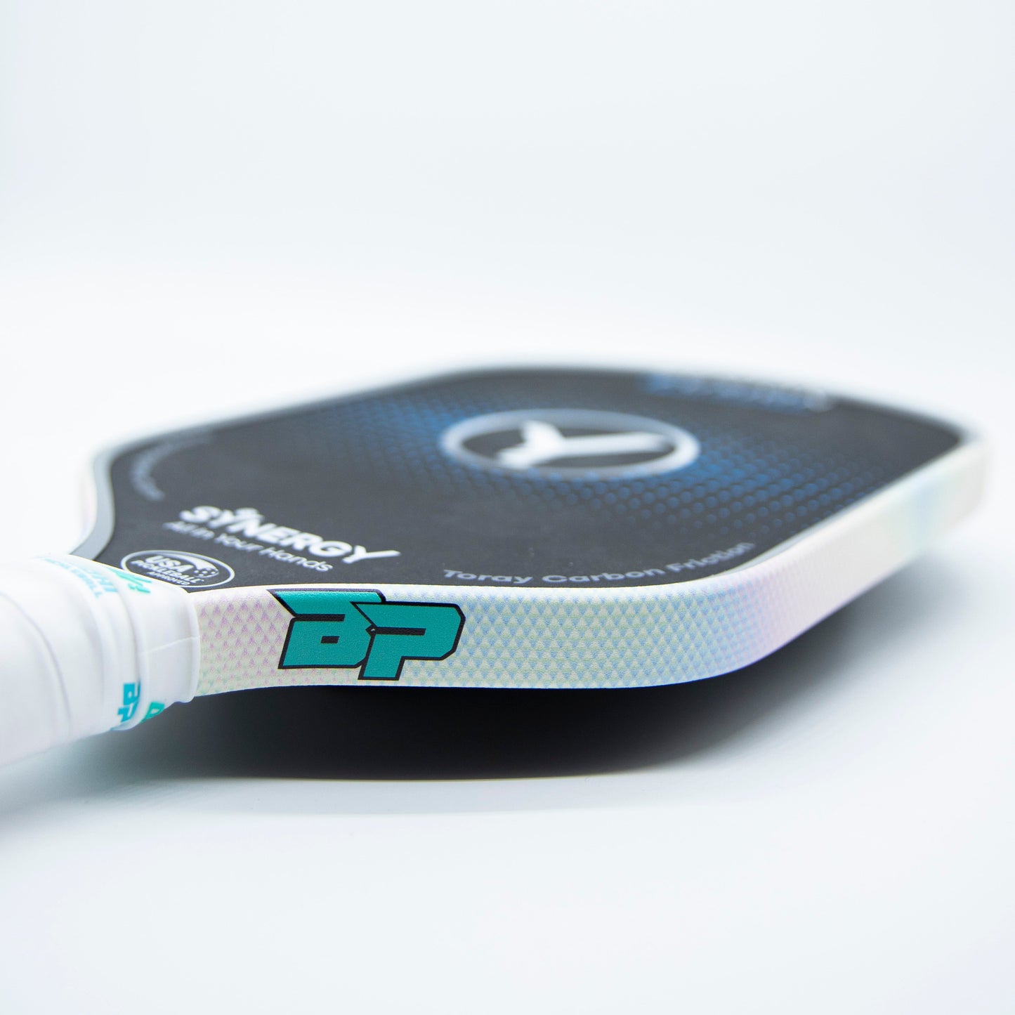 A close-up of a black pickleball paddle with white trim and grip showcases Bodhi Performance’s Premium Edge Tape, offering professional edge guard protection and complementing the turquoise BP branding on its sleek, modern design.