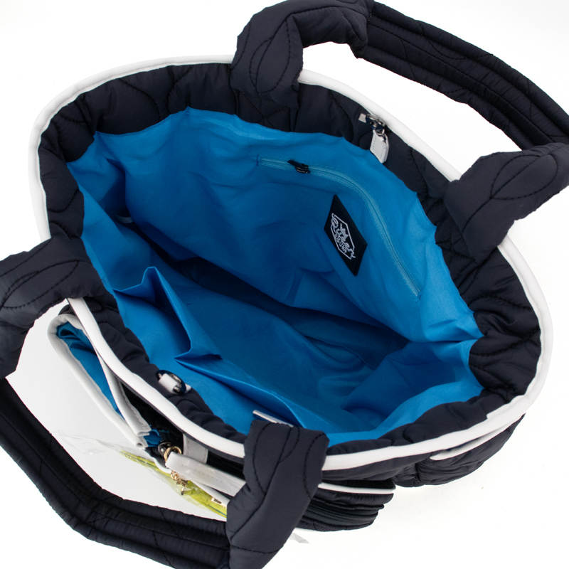 A top-down view of the Queen of the Court Fifth Ave Pickleball Convertible Tote Bag/Backpack reveals a spacious black tote with a light blue interior, zippered pocket, white zipper, padded handles, and white trim—ideal for pickleball enthusiasts.