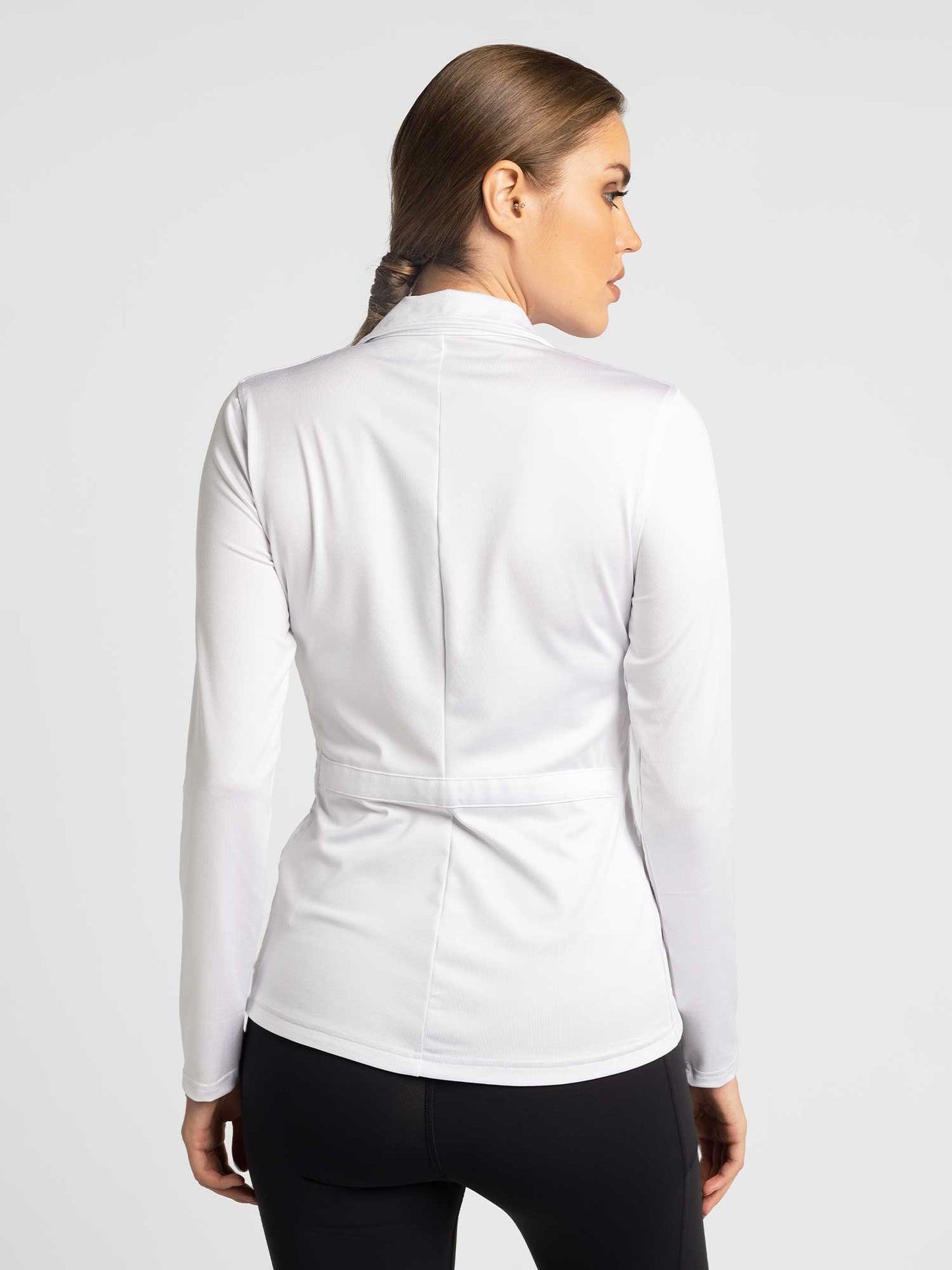 A woman in the Classic Blythe Jacket - White by inPhorm NYC, styled with activewear, exudes casual confidence.