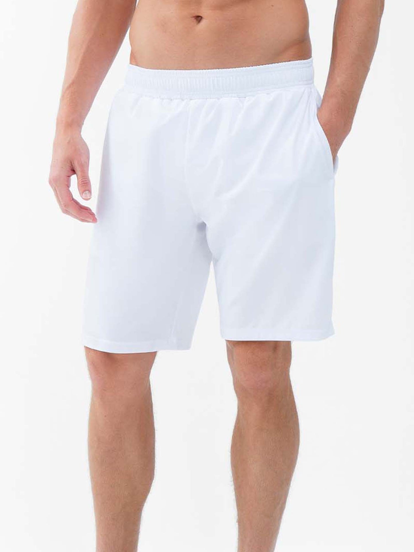 A man models the inPhorm NYC Classic Performance Men's Tennis Short in white, featuring an elastic waistband, side pockets, and quick-dry fabric; shown from mid-torso to knees against a white background, arms relaxed at his sides.