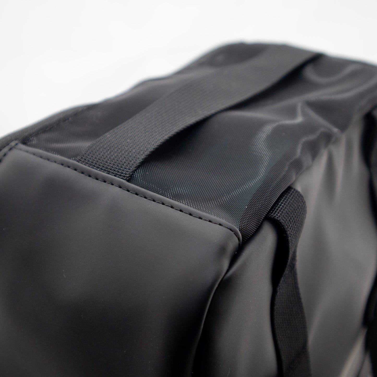 Close-up of the FORWRD Court Caddy Shoe Cube in black, featuring a smooth matte finish, durable stitching, and sturdy fabric handles. The blurred white background highlights the packing cube’s quality texture and strong construction.