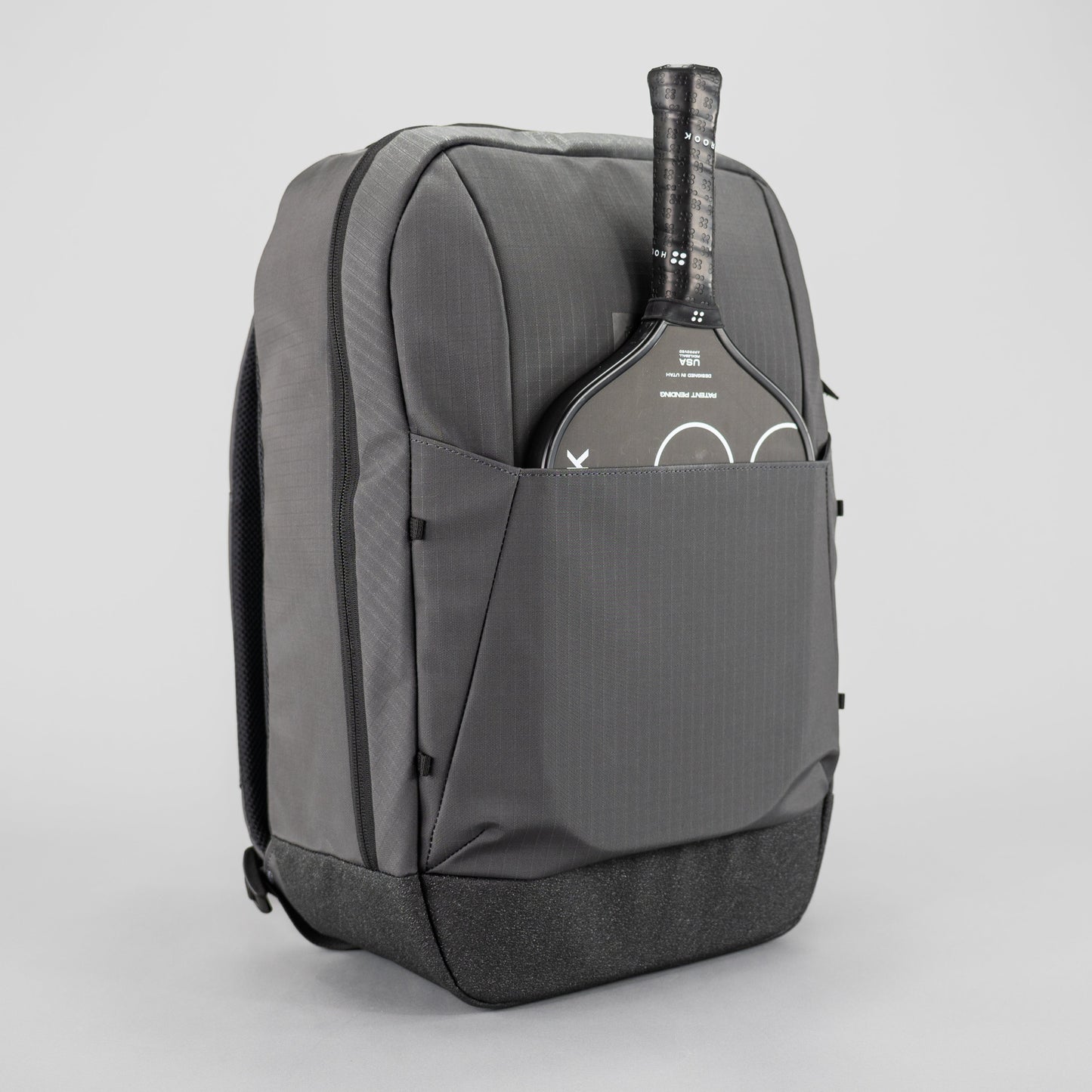 The FORWRD Court Ranger Pickleball Backpack in gray features a front pocket and structured design, easily holding a black paddle with the handle exposed—an ideal pickleball bag for players seeking quality under $200.