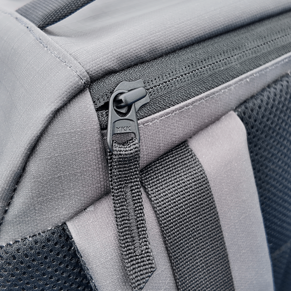 Close-up of the FORWRD Court Ranger Pickleball Backpack’s black YKK zipper, featuring a fabric pull tab and sturdy stitching on gray material with black mesh—showcasing the premium quality of this top pickleball bag.