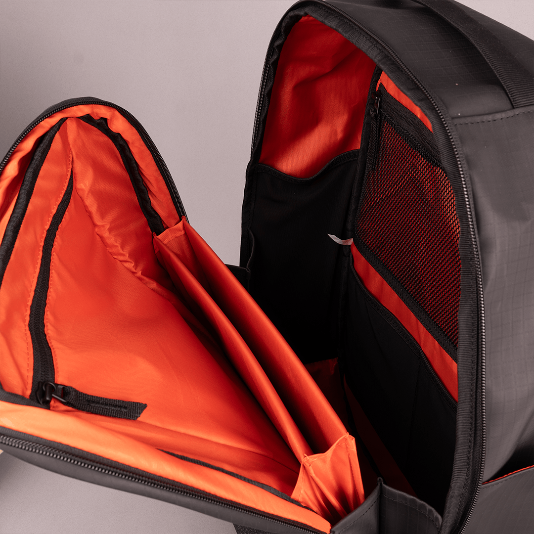 Open FORWRD Court Ranger Pickleball Backpack in black with a vibrant orange interior, showcasing a padded laptop sleeve, mesh zippered pocket, and multiple organizational sections on a light gray backdrop.