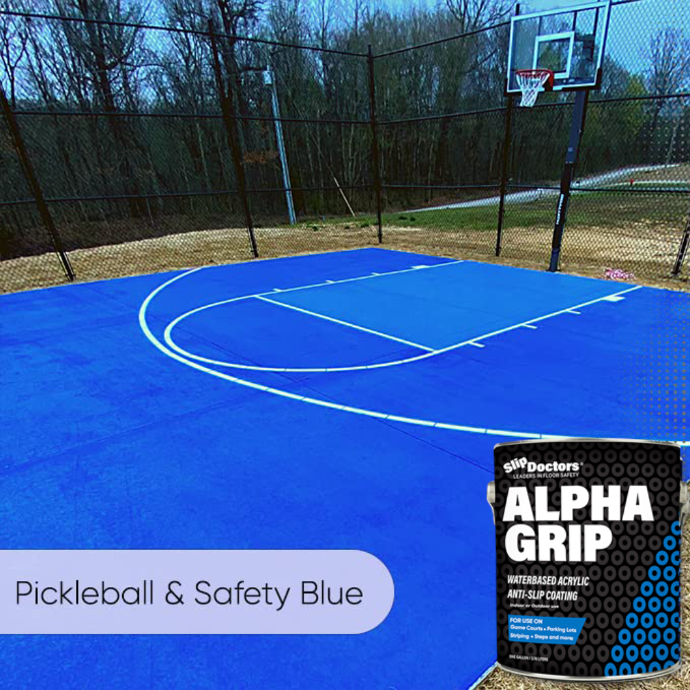 A vivid blue outdoor pickleball court with white lines features SlipDoctors Alpha Grip Non-Slip Stripe and Athletic Court Paint. The court is bordered by a black chain-link fence and trees. Text: Pickleball & Safety Blue.