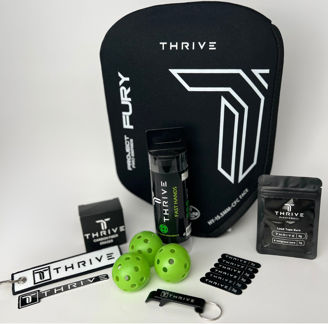 The Thrive Pickleball Cover Add On Bundle ($45 value, Hybrid) includes a neoprene paddle cover, two wristbands, paddle eraser, three green training balls, grip, keychain, ball tube, four oval stickers, pouch, and a white zipper pull—shown on a white background.