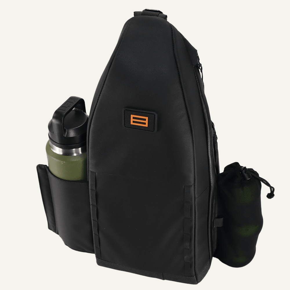 The FORWRD Cross Court Pickleball Sling is a sleek black backpack with an orange logo, featuring a zippered compartment, green water bottle in the left pocket, and a small black mesh bag on the right side.
