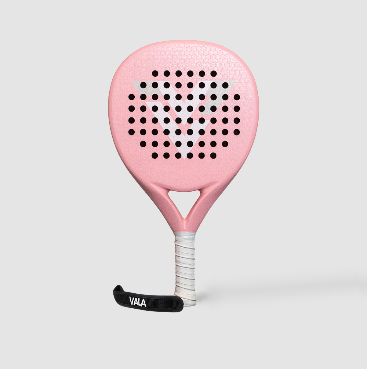 The VALA One (Pink Edition) padel racquet by VALA features a light pink design, perforated head, EVA foam core, white grip with tape, and black wrist strap. It is displayed upright against a plain light gray background.