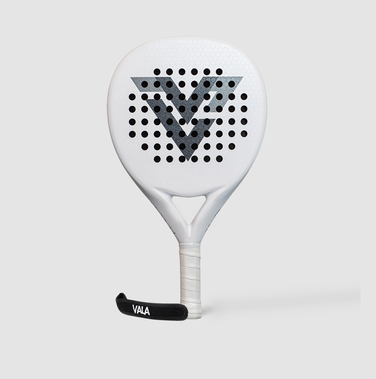 The VALA One (White Edition) by VALA features a perforated face, bold black "V" logo, minimalist white grip, and a black "VALA" wrist strap, all set against a sleek light gray backdrop for premium padel play.