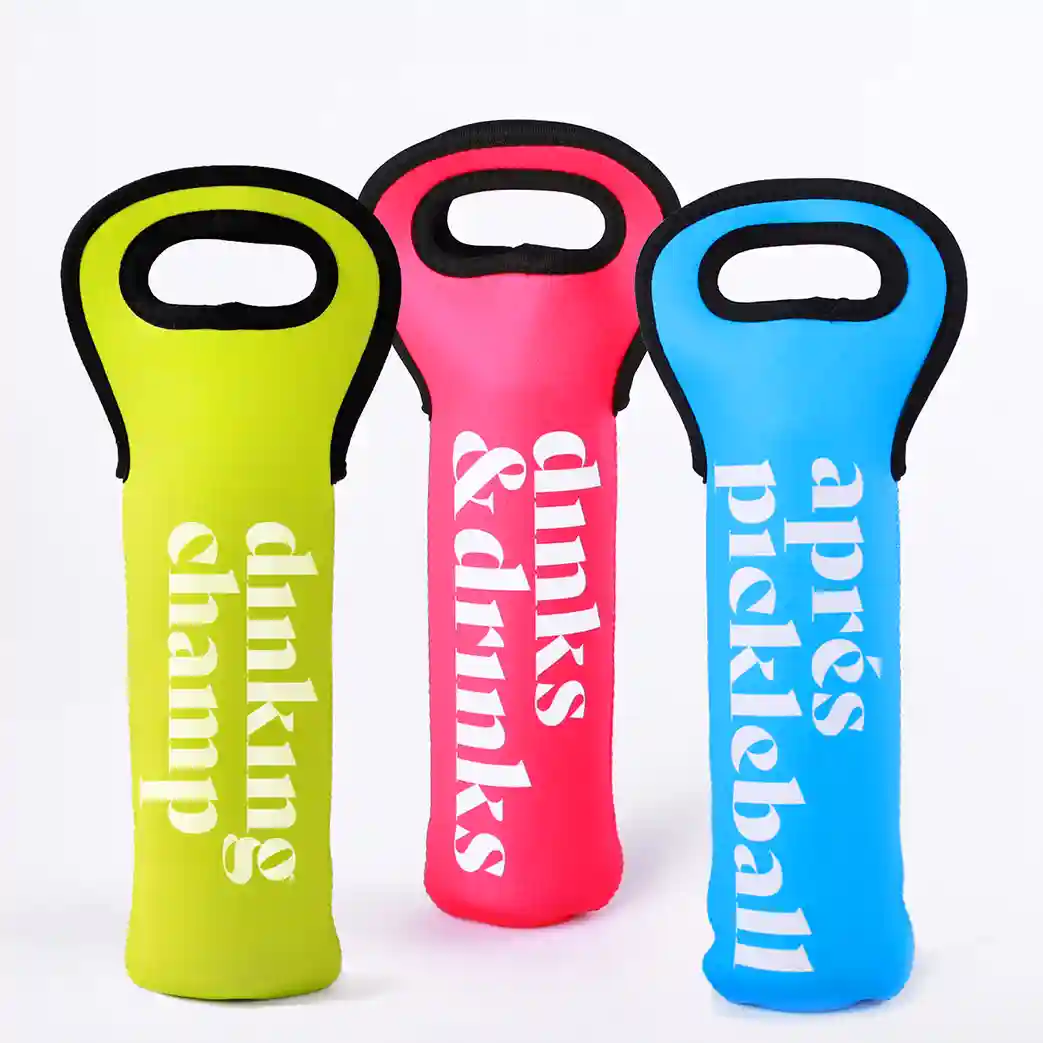 Three vibrant Swinton Pickleball wine tote bags—lime green “Dinking Champ,” pink “Dinks & Drinks,” and blue “Après Pickleball”—pair perfectly with the Dinking Champ Sleeve of Pickleballs for your next match or picnic.