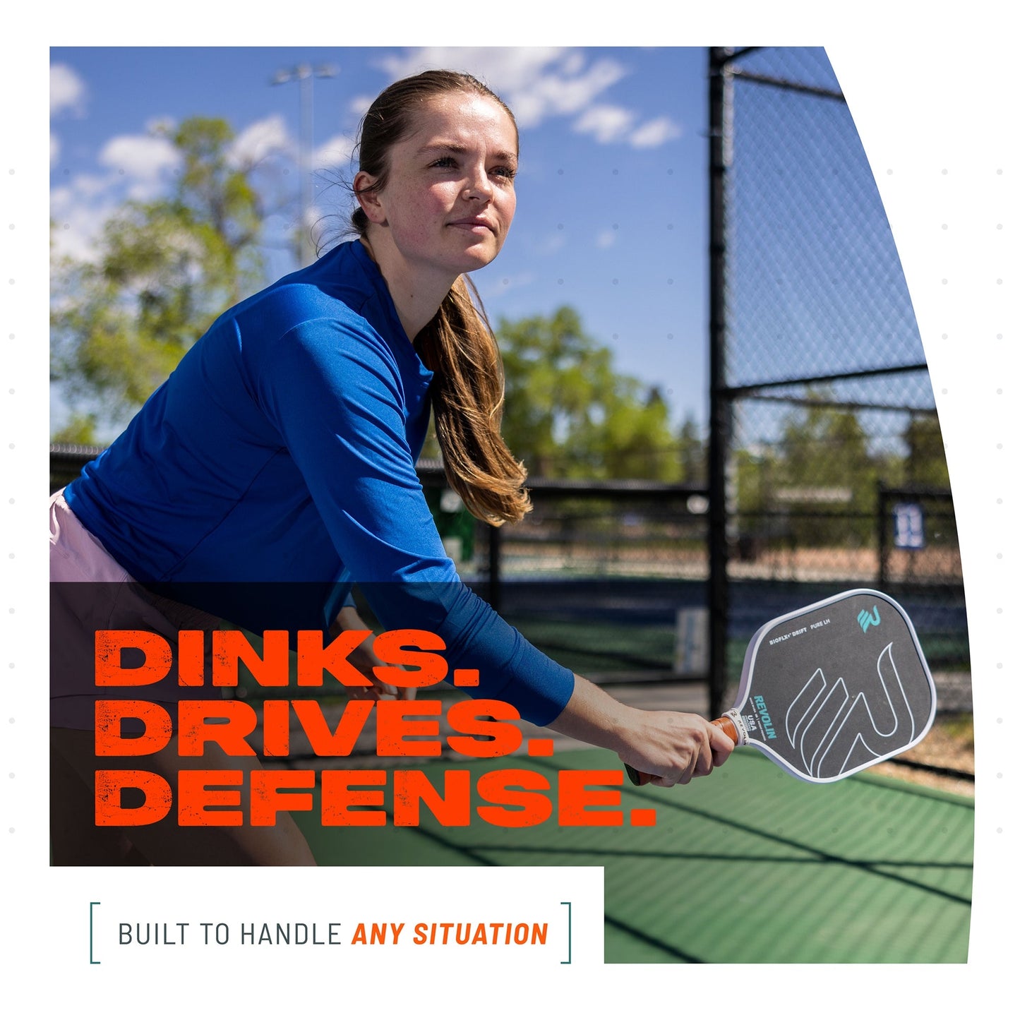 A young woman in a blue top readies her Drift Reach Pickleball Paddle by Revolin Sports, featuring a honeycomb core, on an outdoor court. "DINKS. DRIVES. DEFENSE." appears in bold orange; below: "BUILT TO HANDLE ANY SITUATION.