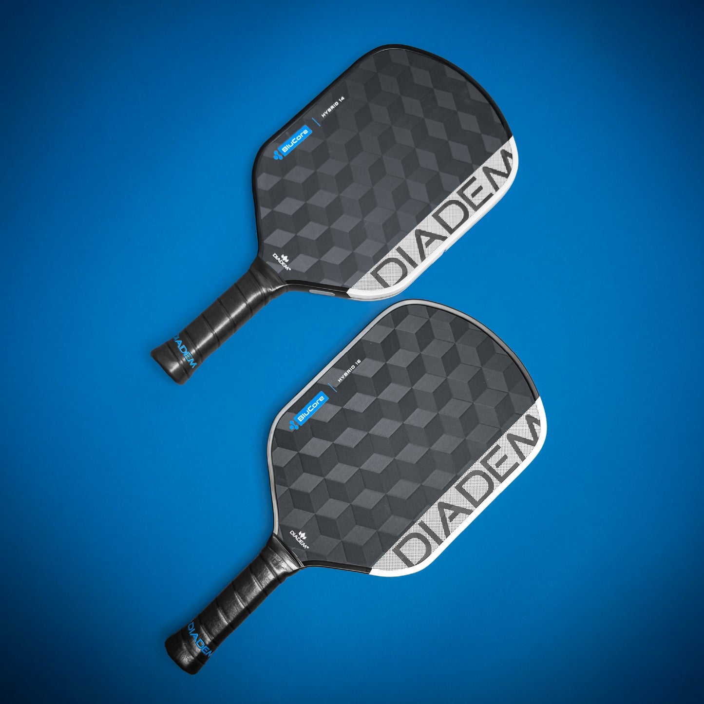 Two black Diadem Sports Edge BluCore Hybrid paddles with textured hexagon patterns are arranged diagonally on a blue background. Both USAPA-approved paddles feature the DIadem logo in white and have black handles with blue accents.